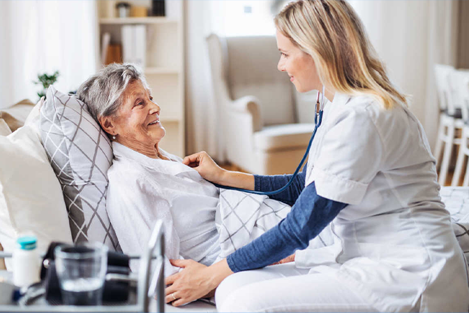 Nurse examining elderly woman in bed.