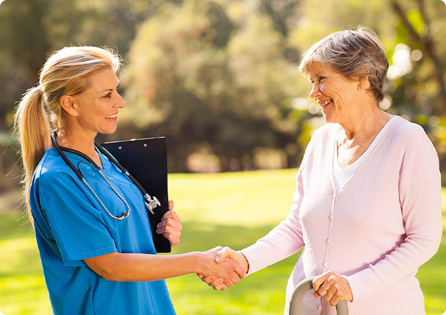 Smiling nurse shakes hand of senior patient.