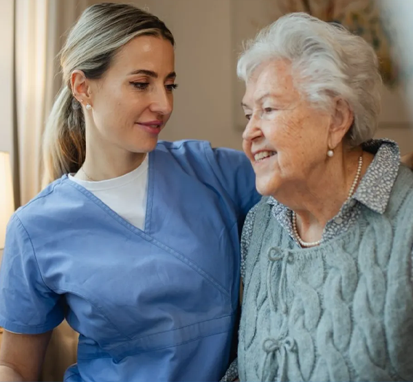 Smiling nurse and happy elderly woman in home care setting.
