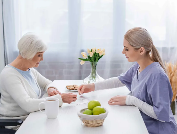 Caregiver and senior woman playing a puzzle at a table.