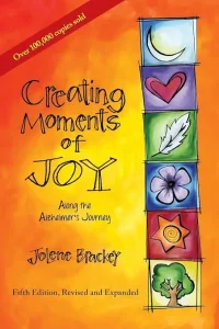 Book cover of “Creating Moments of Joy,” a guide for supporting people living with Alzheimer’s, featuring colorful illustrated symbols
